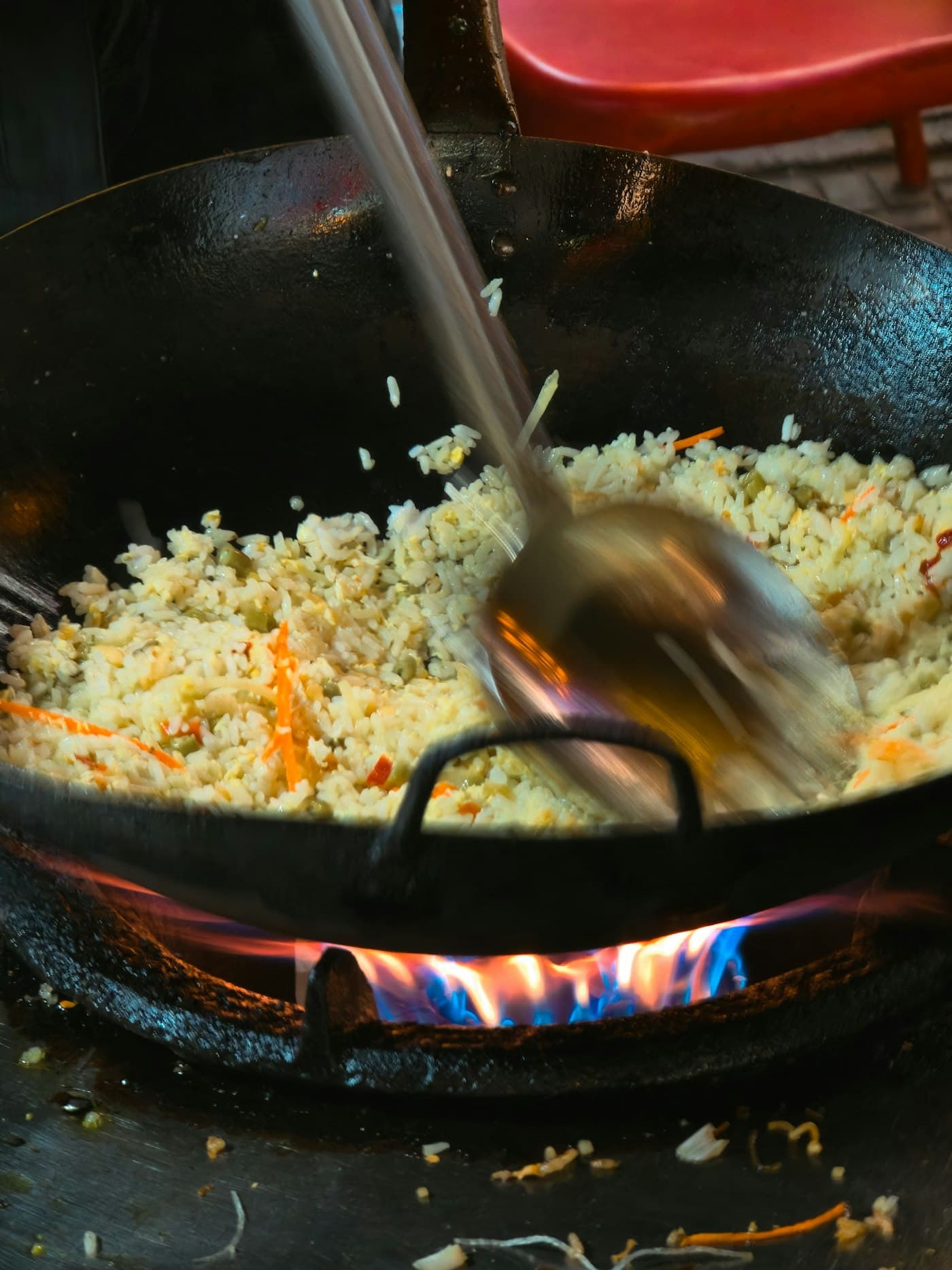 Riz sauté remué dans un wok au-dessus de la flamme